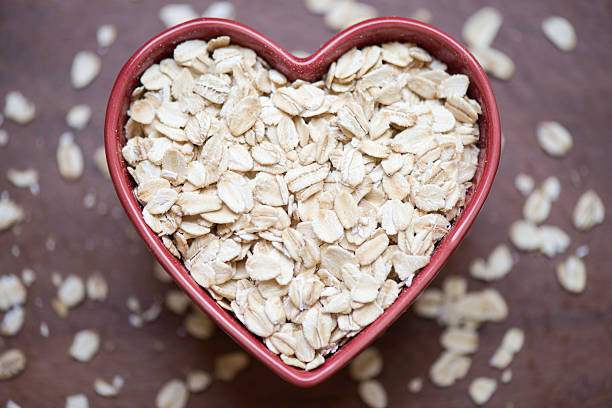 gesunder hafer - oatmeal oat heart shape rolled oats stock-fotos und bilder