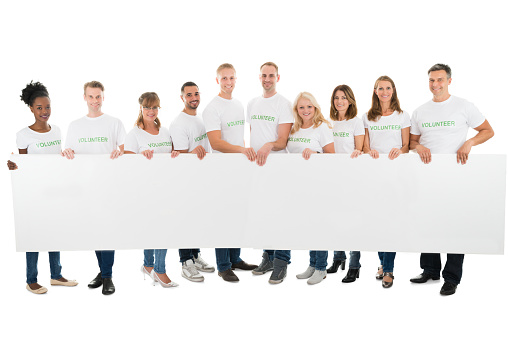 Full length portrait of confident volunteers holding blank billboard against white background