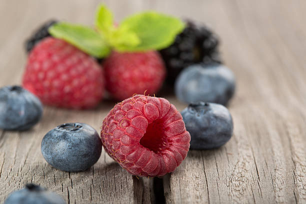 istock Mix of different berries on the old a wooden table 591415438