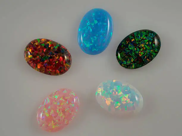 Colorful set of unmounted mosaic, blue, red, pink, and white opals displaying brilliant fire flashing color 