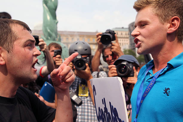 Republican National Convention, July 21, 2016 Cleveland, Ohio, USA - July 21, 2016: A young member of the IWW (Industrial Workers of the World), an international union with roots in the socialist and anarchist labor movement, argues about economic systems with another young man during an unauthorized IWW march on the fourth, and final, day of the Republican National Convention. There was a heightened level of tension on the streets on the afternoon and early evening of the last day. rnc stock pictures, royalty-free photos & images