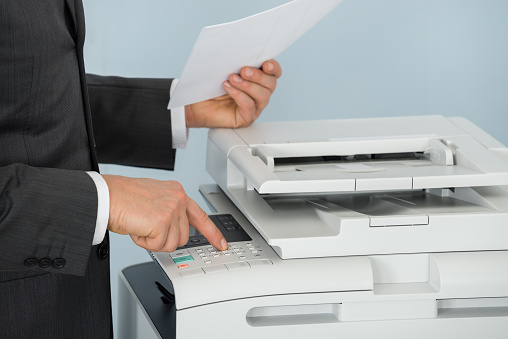 Close-up Of Businessman Hand Pressing Printer's Button In Office