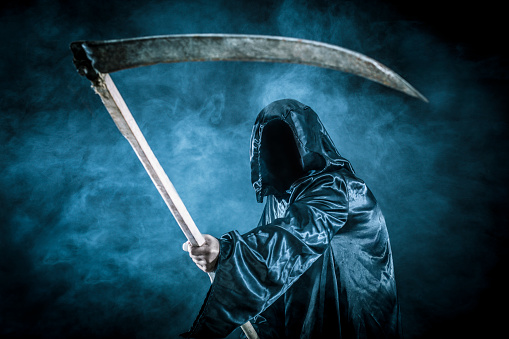 Grim reaper with scythe on dark misty night.
