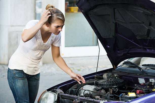 istock Confused Woman Looking At Broken Down Car Engine 591421438