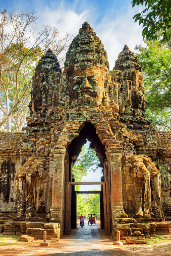 Gateway to ancient Angkor Thom in Siem Reap, Cambodia. Gopura with stone face on woods background. Enigmatic Angkor Thom is a popular tourist attraction.