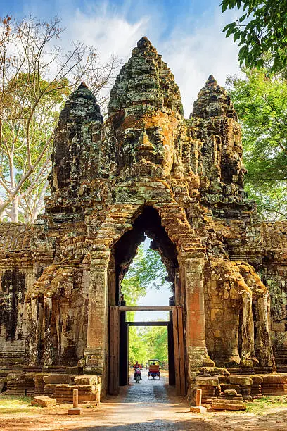 Gateway to ancient Angkor Thom in Siem Reap, Cambodia. Gopura with stone face on woods background. Enigmatic Angkor Thom is a popular tourist attraction.