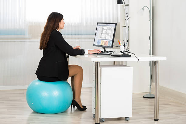 istock Businesswoman Using Computer While Sitting On Pilates Ball 591423348