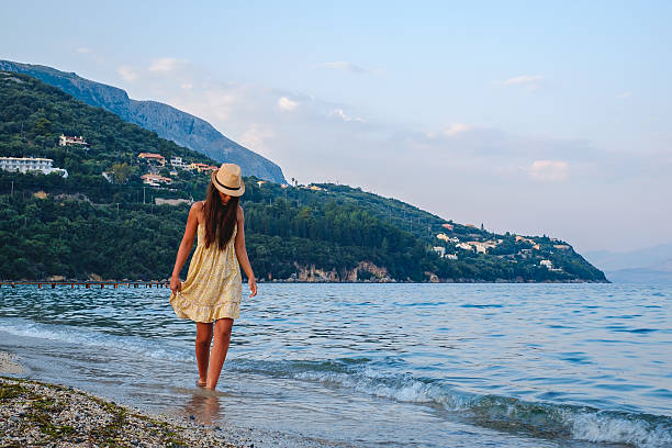 istock Girl with hat walking by the sea 591424876