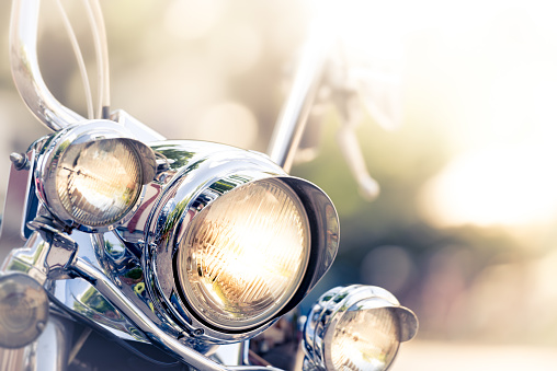 Motorcycle detail with headlamps in foreground and blurred nature background. Travel by motorbike.