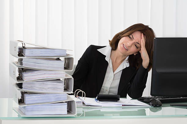 istock Stressed Businesswoman Looking At Stack Of Folders 591426468