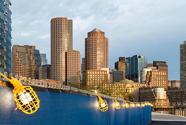 Temporary lighting setup Lighted walkway near new construction along Harborwalk in South Boston with Rowes Wharf skyline in background harborwalk stock pictures, royalty-free photos & images