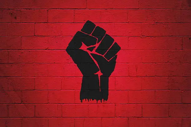 Black fist painted on a red brick wall. Ideal to serve as wallpaper or the base for a bigger composition.