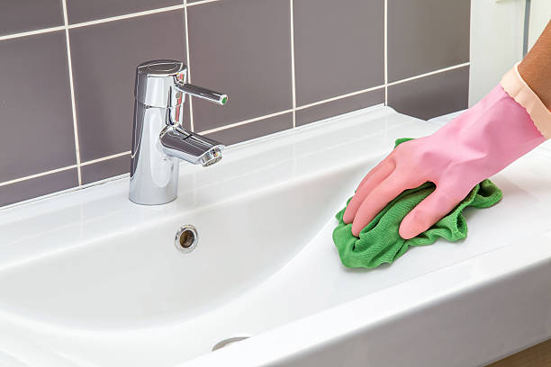 In the bathroom, ceramic sink, tiles and water tap washing. In the bathroom, ceramic sink, tiles and water tap washing and polishing. Maid or housewife cleans house. General cleaning or regular wash up. formal glove stock pictures, royalty-free photos & images