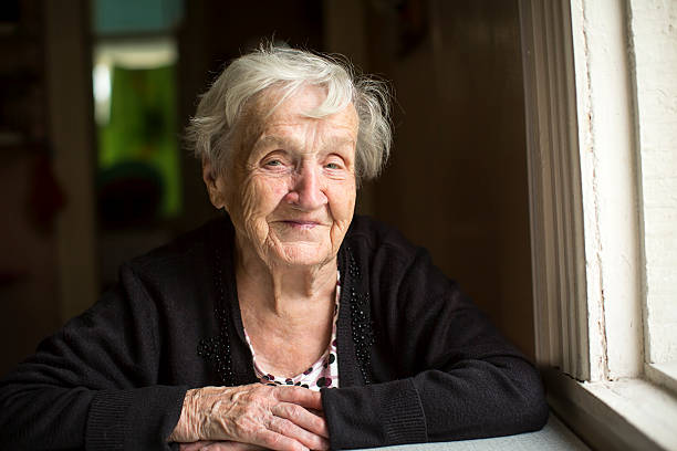 istock Elderly woman smiling sitting at the table. 591445686