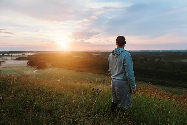 istock Runner looks at scenic sunset view from hill top 591447650