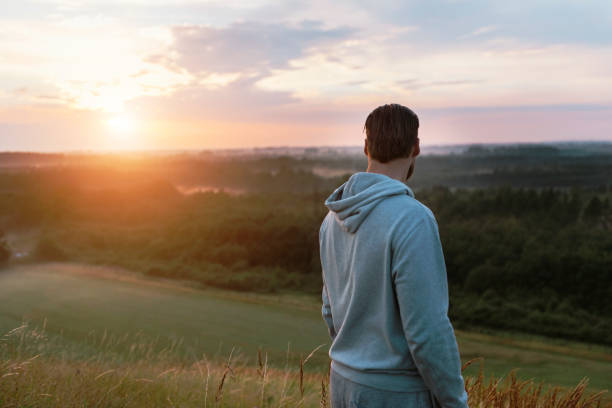 istock Runner stands on hill overlooking scenic view at sunset 591447706