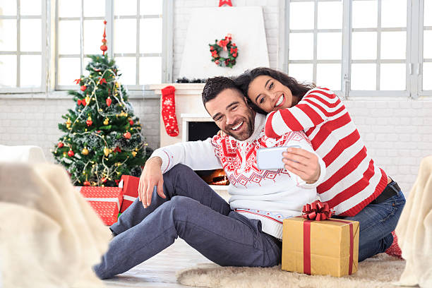 istock Young couple sitting on ground and making selfie at home 591783630