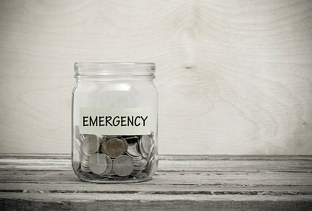 emergency Label on a glass jar with the inscription - emergency. Glass jar with coins. Financial concept on wooden background cent sign photos stock pictures, royalty-free photos & images