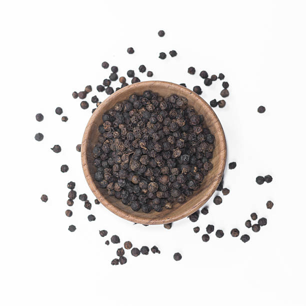istock Black pepper in wooden bowl isolated on white background 591807494