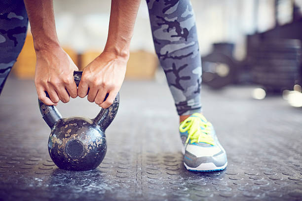 istock Low section of female lifting kettlebell on gym floor 591809452