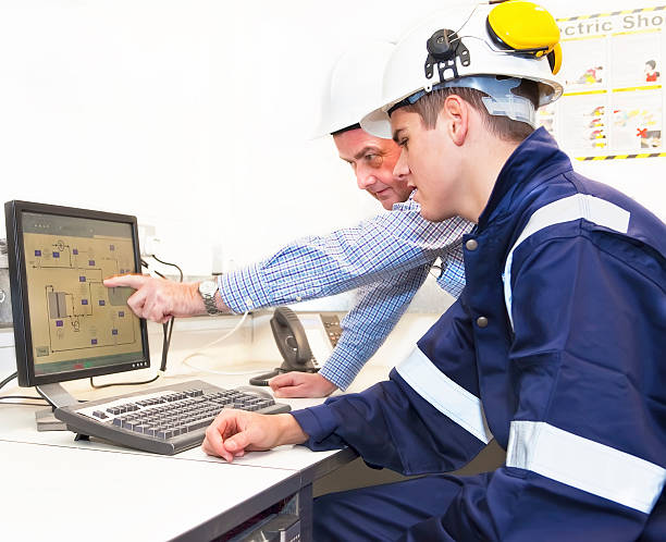 Senior and junior engineers discussing work together in office