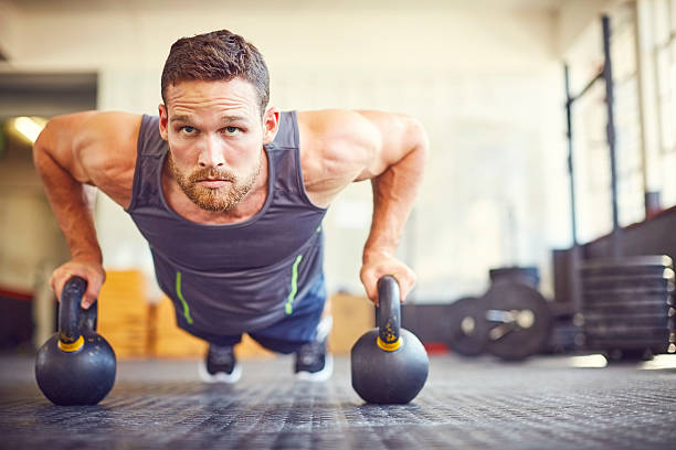 istock Focused athlete doing push-ups on kettlebells in gym 591812962