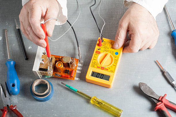 istock Hand of electrician with multimeter probe at  electrical switchgear cabinet 591813096