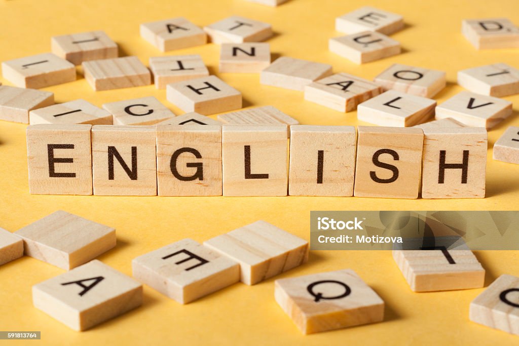 Word english made with block wood letters next to a Word english made with block wood letters next to a pile of other letter over wooden table. England Stock Photo