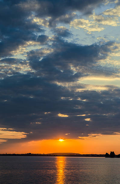 istock Orange sunset over a european lake, blue clouds sky 591815662