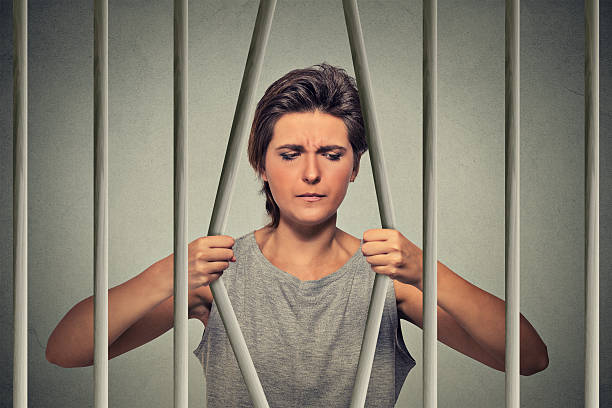 Stressed desperate woman bending bars of prison cell