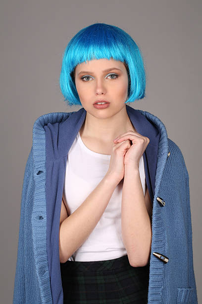 girl in blue wig and coat compressing her arm. close - shirt fine art portrait vertical head and shoulders imagens e fotografias de stock