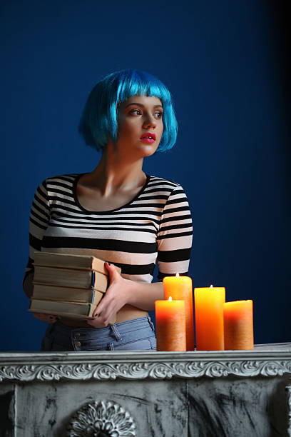 model in blue wig posing with books and candles. close - shirt fine art portrait vertical head and shoulders imagens e fotografias de stock