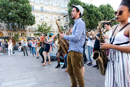 Paris, France - July 7, 2016: The bare brass band busking at Paris, France (Saint-Michel District). young musicians are playing some instrument and earning money by using classic musical instruments (trombone, saxophone, oboe, drums, tuba, horn) in street of Paris. They are street musicians.