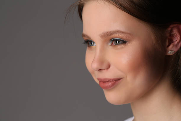 istock Smiling lady with makeup lookng away. Close up. Gray background 591822238