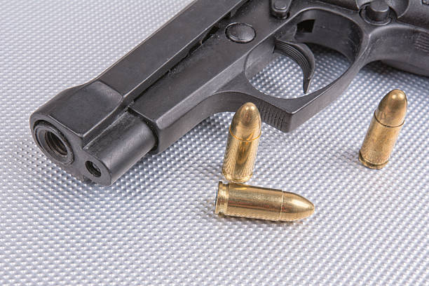 istock Bullets and gun on aluminium background 591825416