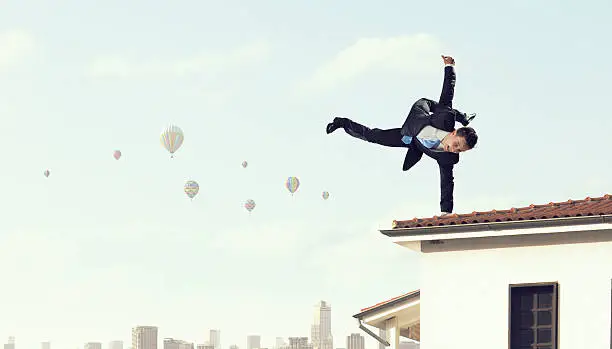 Active businessman making handstand on house roof