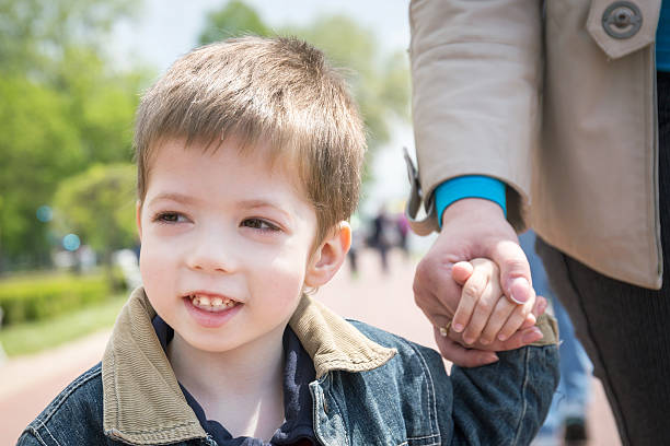 istock young boy holding hand in hand with his mother 591829712