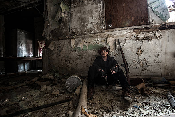 istock Man sitting with gun while Smoking in Abandoned Building 591830876