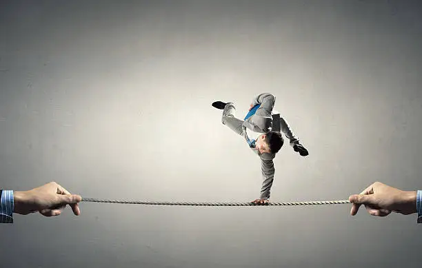 Active young businessman making handstand on rope
