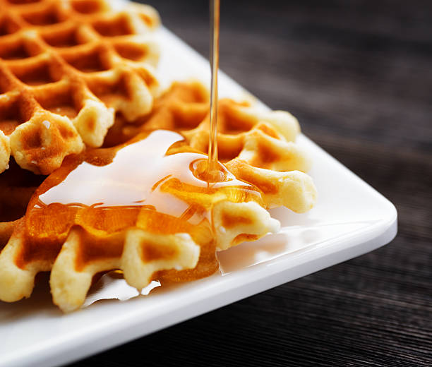 honig eingießen auf einem frischen waffeln. - waffle syrup pouring breakfast stock-fotos und bilder