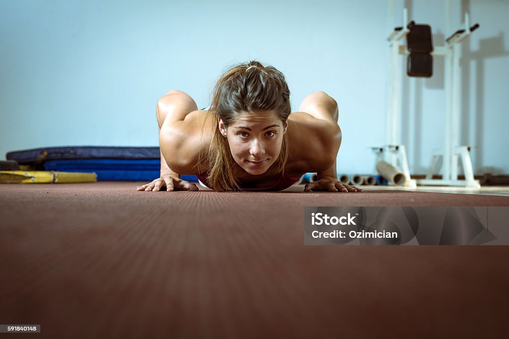 Girl doing push-ups in gym Young adult girl doing push ups exercise in gym Activity Stock Photo