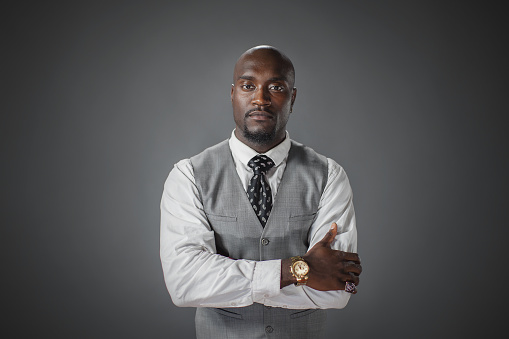 A well dressed confident African-American male studio shot with arms crossed and looking at the camera.