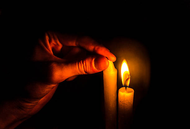 istock hand turning off a candle, another of fire 591841416