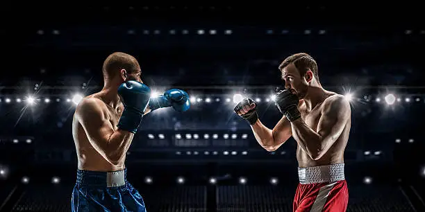 Two professional boxers fighting on arena in spotlights 