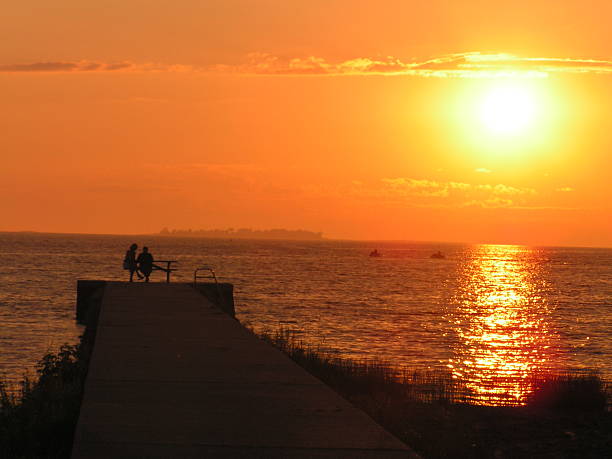 Rear view of romantic couple enjoying the view on a pier at sunset.