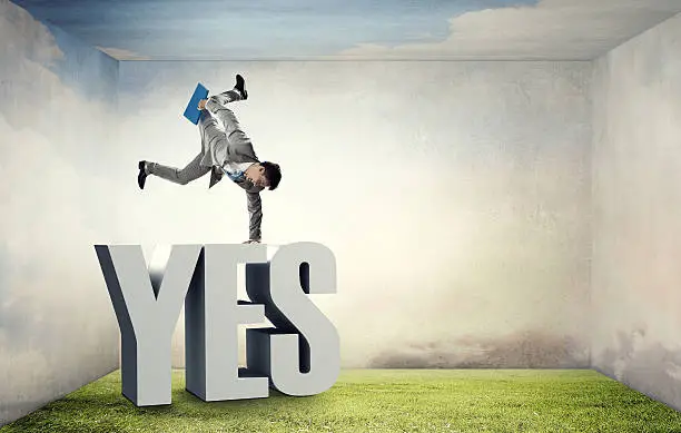 Active businessman making handstand on word yes