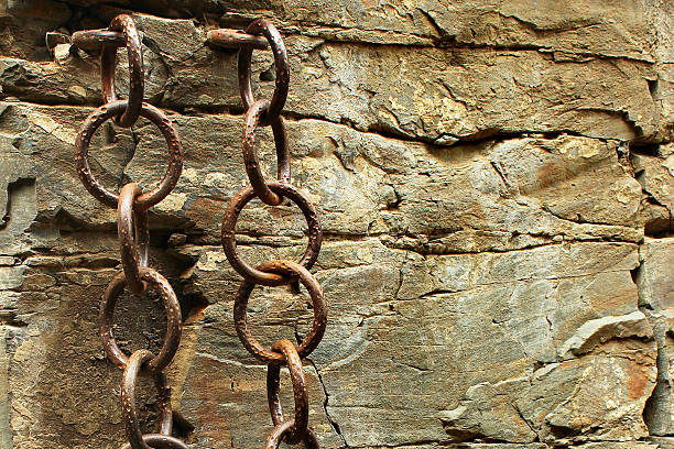 istock Old metal chains in the rough stone wall 591849120