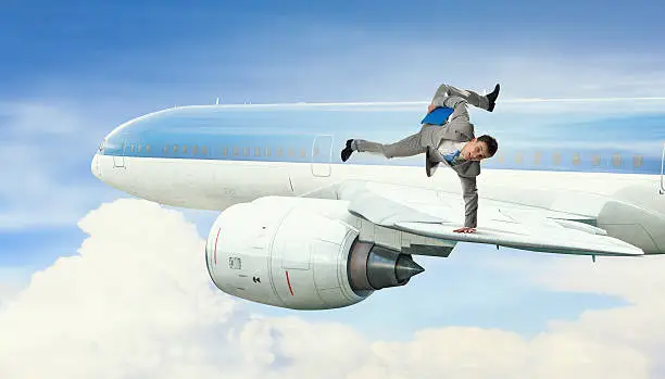 Active businessman making handstand on airplane wing