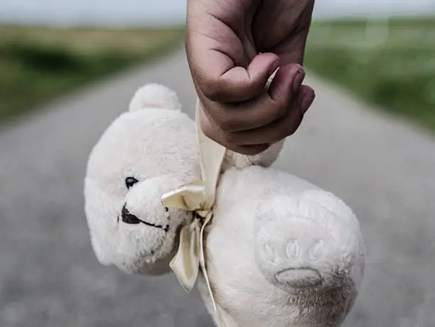 Girl goes with her teddybear on the road, close up