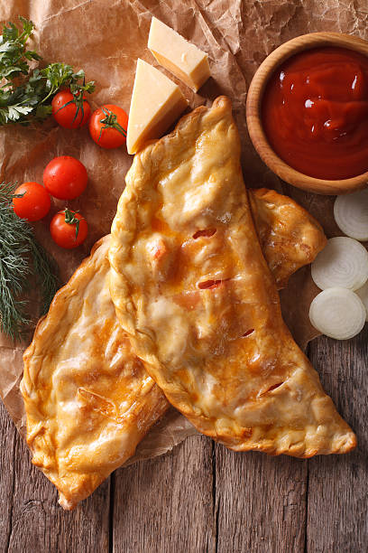istock pizza calzone closeup on a paper and ingredients 591993272
